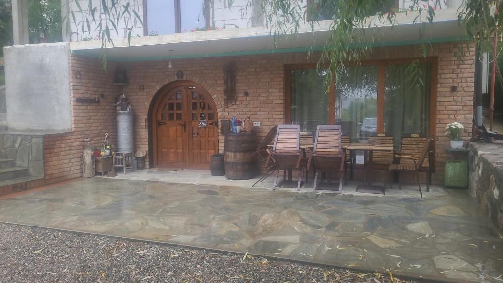 a patio with a table and chairs and a building at Casuța din livada in Albestii de Arges