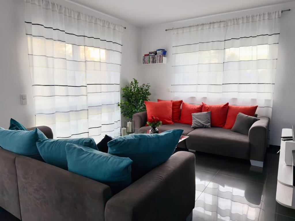 Una sala de estar con un sofá y almohadas rojas. en Ferienwohnung "Thermenblick - Bad Aibling", en Bad Aibling