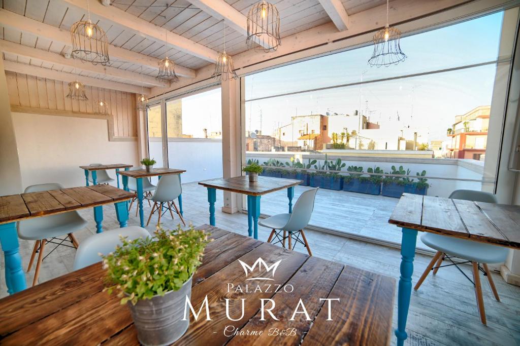 ein Restaurant mit Tischen und Stühlen und einem großen Fenster in der Unterkunft Palazzo Murat B&B in Monopoli