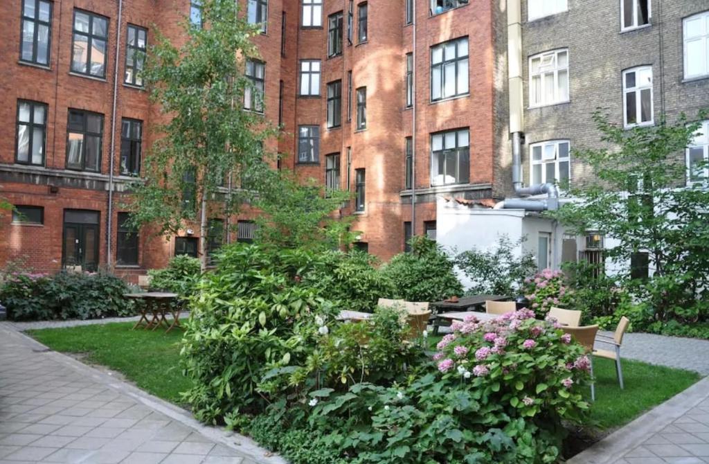 een tuin voor een groot bakstenen gebouw bij Quiet room in lively area with helpful Host! in Kopenhagen