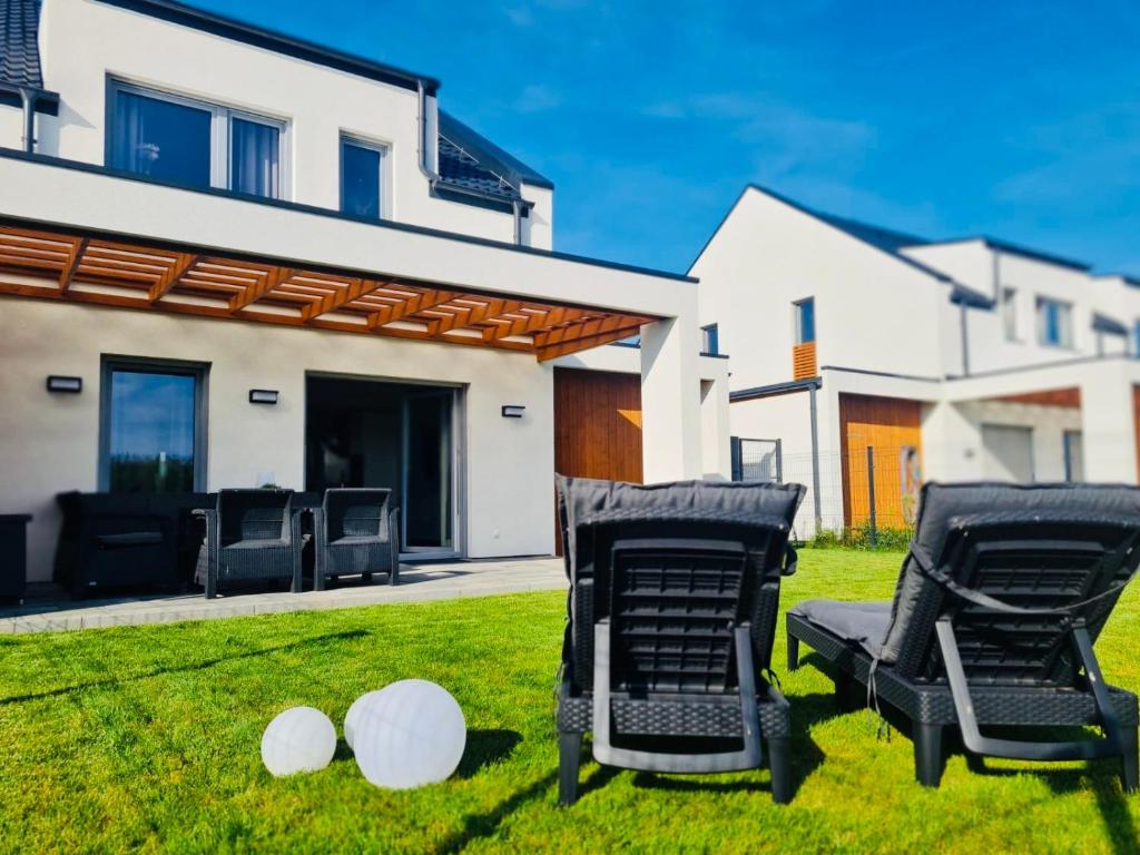 two chairs on a lawn in front of a house at Moana House LAURA in Trzęsacz