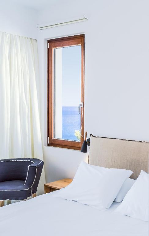 a bedroom with a bed and a chair and a window at Semeli in Kokkari