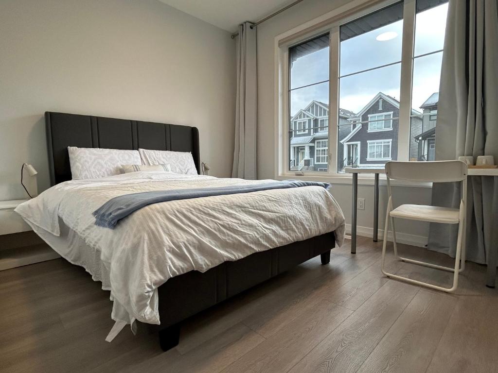 a bedroom with a bed and a chair and a window at Sunny Queen-size Bedroom with Private Bath in Brand New House in Calgary