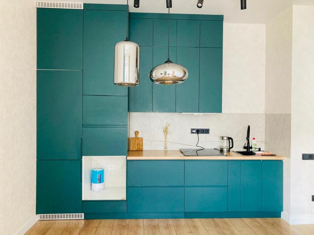 Una cocina con gabinetes azules y un fregadero. en Современные, светлые и уютные апартаменты в центре Астаны, en Astana