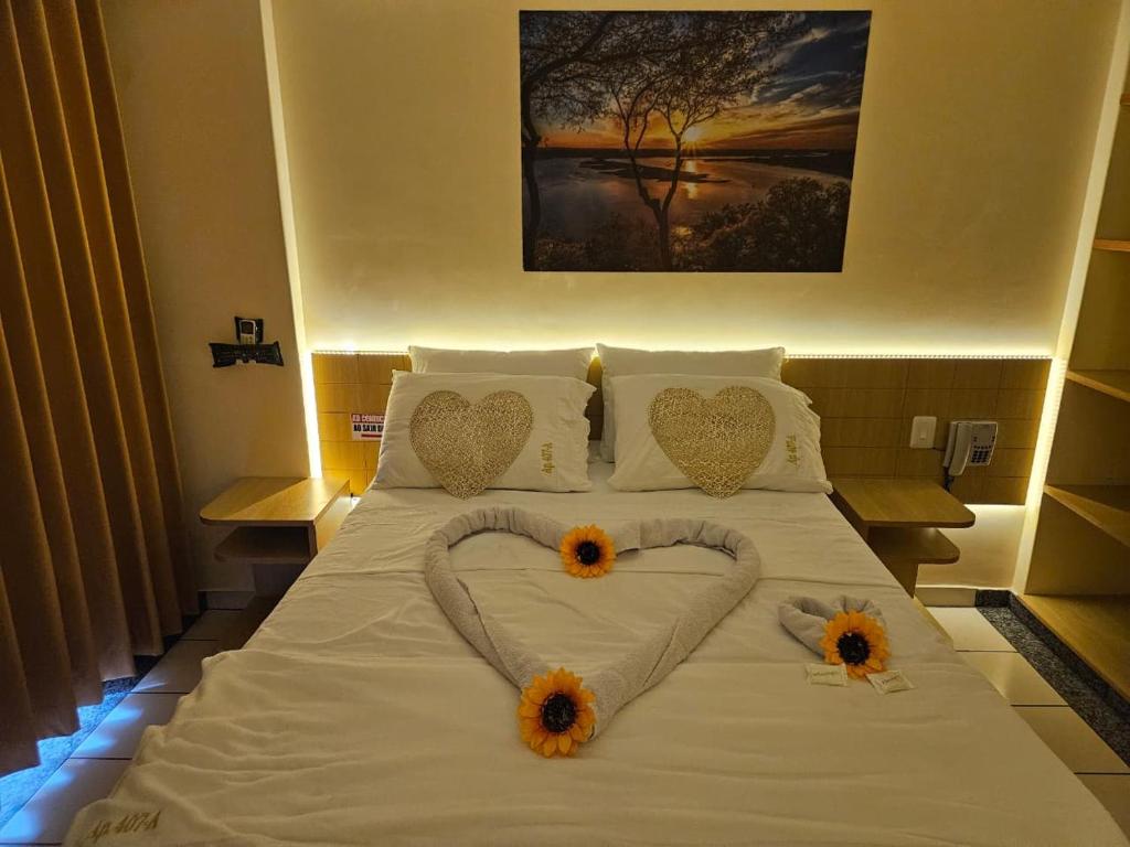 Una cama con dos corazones y dos girasoles encima. en Flat Di Roma Aconchego1 em Rio Quente Go - Hot Park, en Rio Quente