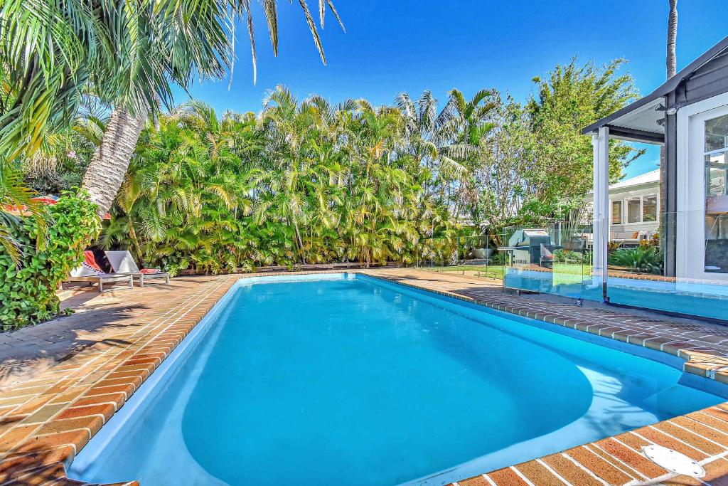a swimming pool in the backyard of a house with palm trees at Tosca Elegant Merewether Beach House with Pool in Merewether