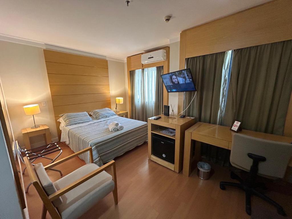 a hotel room with a bed and a desk with a computer at Hotel lindo Aeroporto Congonhas com garagem e piscinas 1703 in Sao Paulo