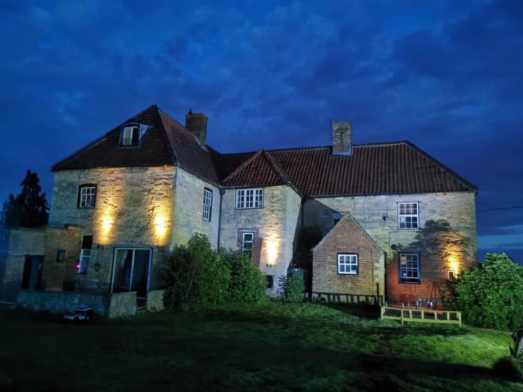 an old stone house with lights on it at night at Countrylife Cottage for Groups- BBQ , firepit, free parking in Lincoln