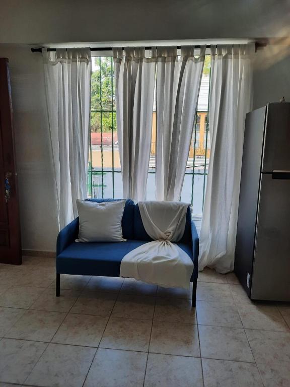a blue couch sitting in front of a window at J. B Apartamentos in Santo Domingo