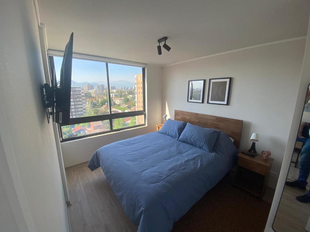 a bedroom with a blue bed and a large window at Nuñoa a un paso de todo lo que necesitas in Santiago
