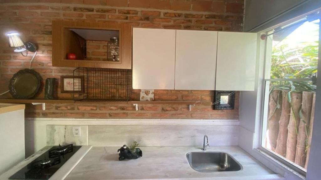 cocina con fregadero y pared de ladrillo en Cabana graciosa e aconchegante, en Jaguariúna