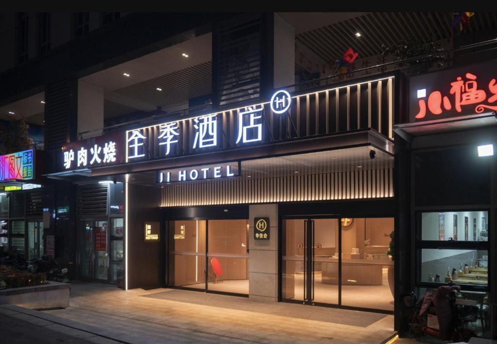 een hotelbord aan de zijkant van een gebouw 's nachts bij JI Hotel Qingdao Laoshan MixC in Qingdao