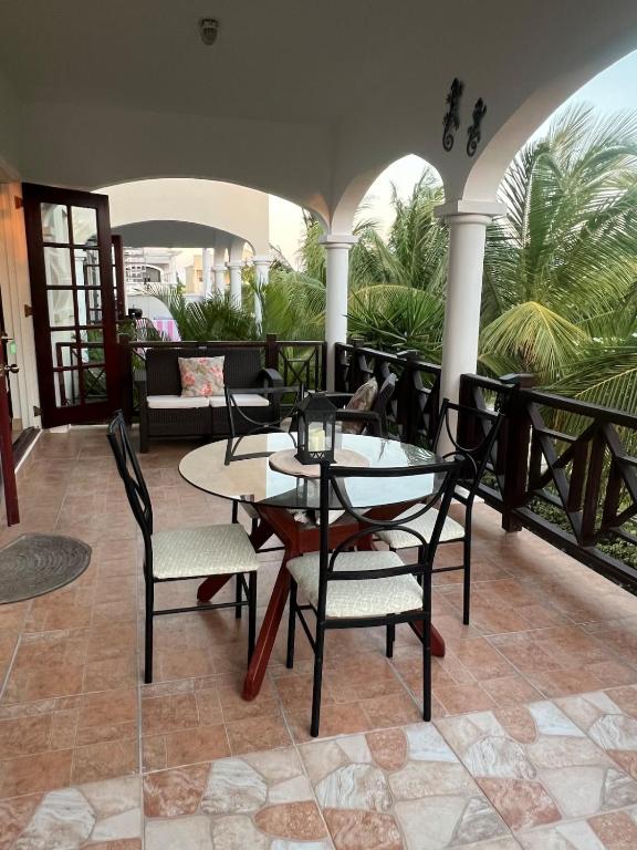 a patio with a table and chairs on a porch at Oistins Gem 2BR, 2BA Condo, Pool & Rooftop Patio, Walk to Miami Beach in Christ Church