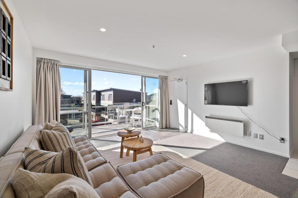 a living room with a couch and a television at Chic City Apartment, Sleeps 7, Pool, Gym & 2 Parks in Christchurch