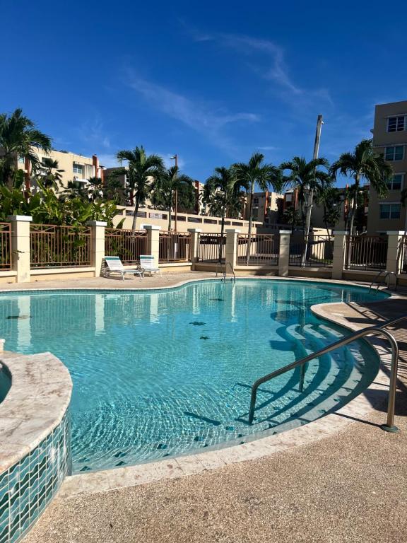 a large swimming pool with chairs and palm trees at The Choliseo Bayside Stay in San Juan