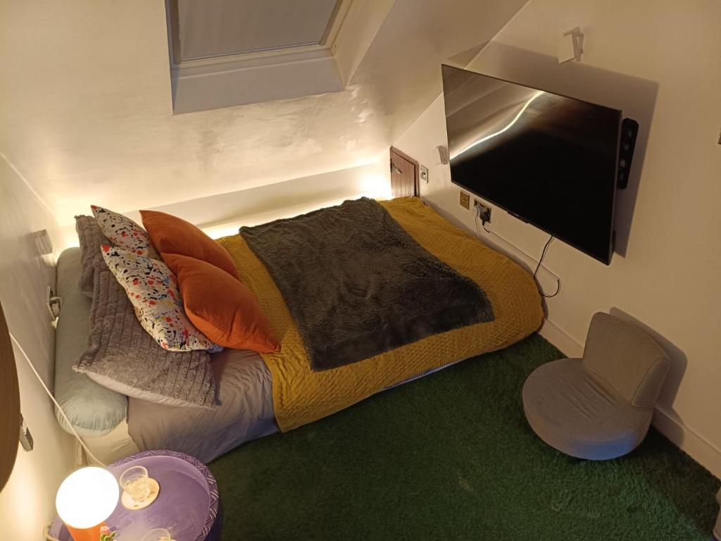 Un dormitorio con una cama grande y un televisor de pantalla plana. en The Snug in a Quaint English Mews House, en Londres