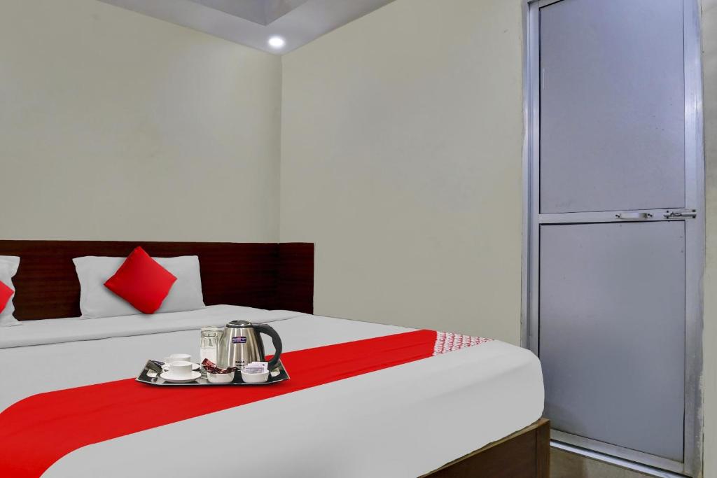 a bedroom with a white bed with a red blanket at Hotel O Arjun in Prayagraj