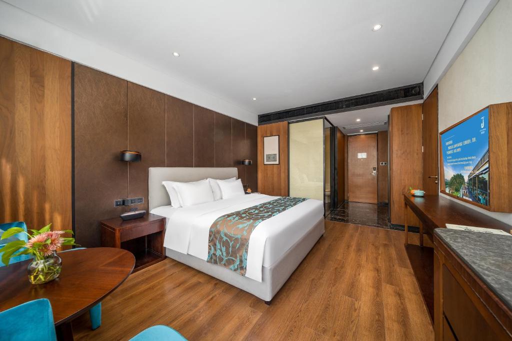桂林市にあるJolie Vue Boutique Hotel Guilin (near Elephant Trunk Hill)のベッドとテーブルのあるホテルの部屋
