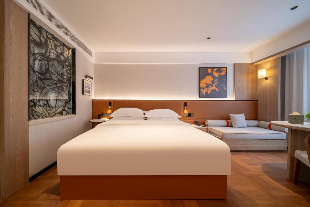 een slaapkamer met een groot wit bed en een bank bij Mehood Lestie in Jinghong