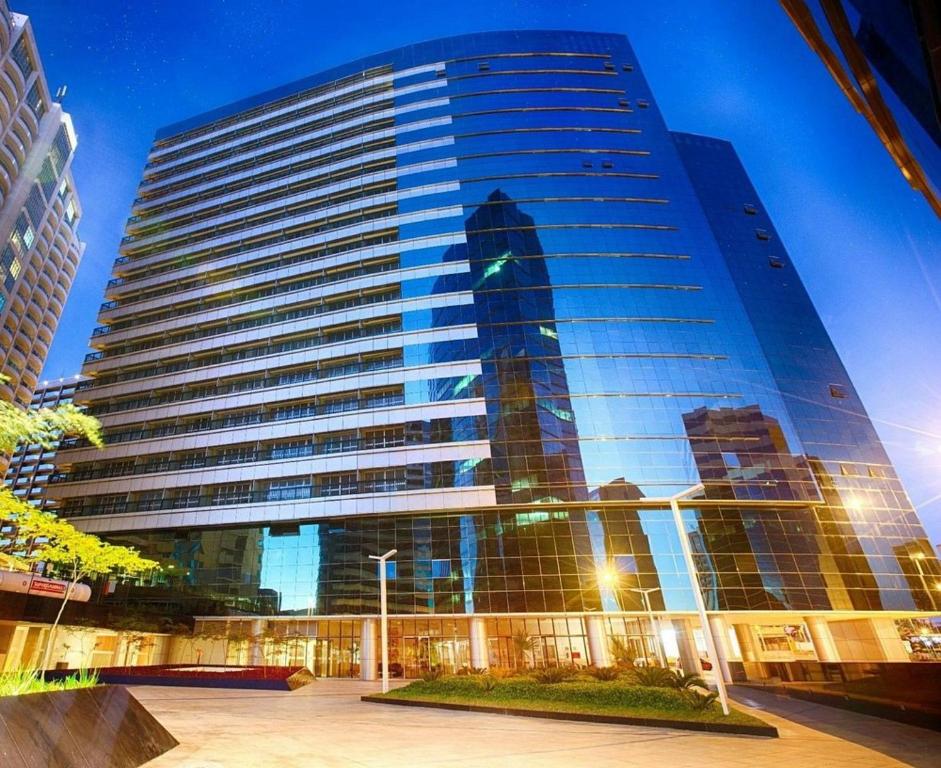a tall building with the reflection of a skyscraper at Alugueasy - Hotel Fusion in Brasilia