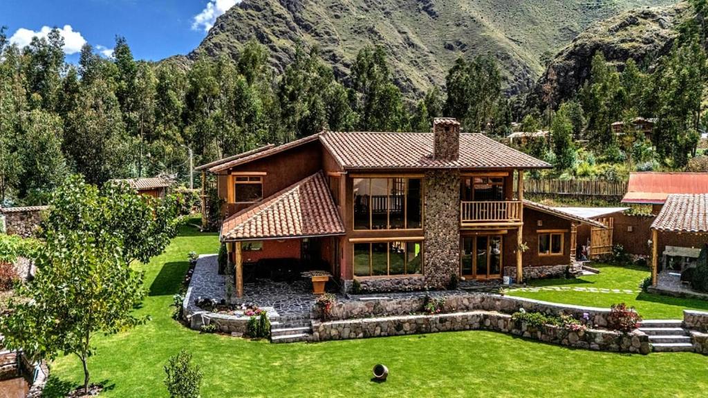 a house with a large yard in front of a mountain at Flor de Amancay Villas - Sacred Valley in Calca
