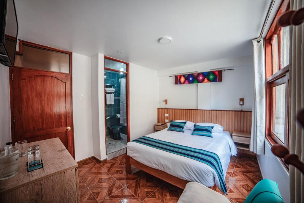 a bedroom with a bed with blue pillows at Casa Andora in Machu Picchu