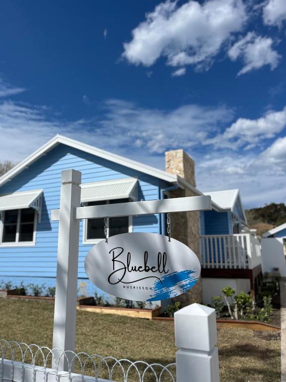 a sign in front of a blue house at Bluebell Huskisson in Huskisson
