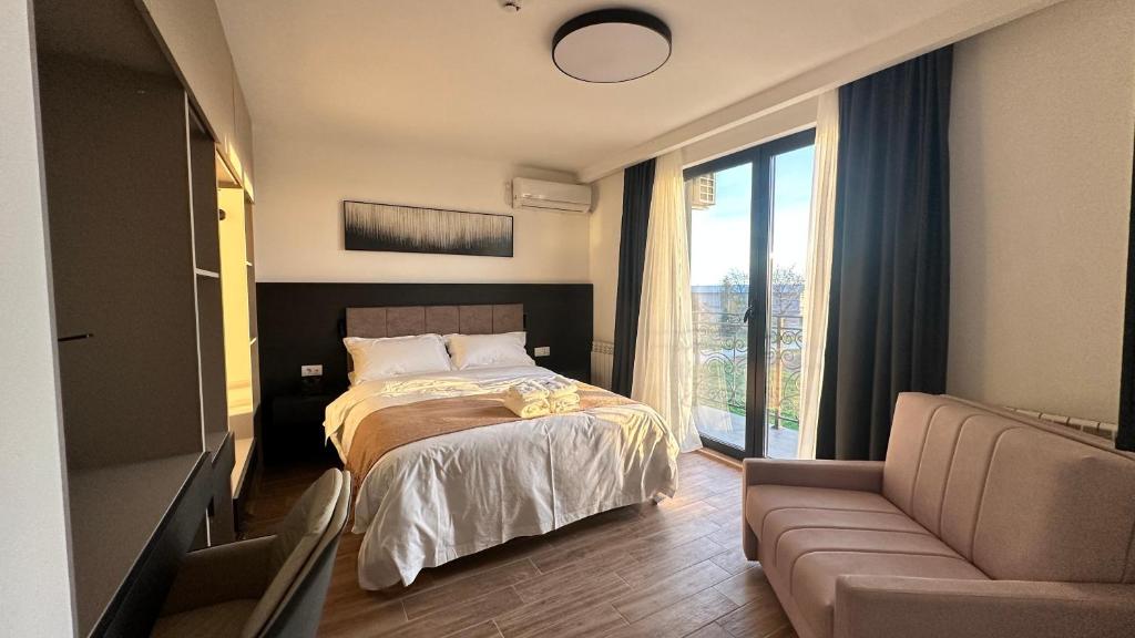 a bedroom with a bed and a couch and a window at KIMMIY hotel贝尔格莱德可眯酒店 in Beograd