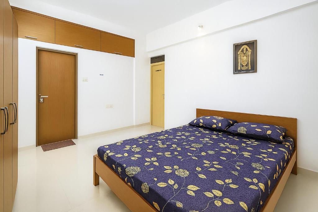 ティルパティにあるNew Spacious 2BHK apartments in Tirupati Near Railway Station with fully equipped kitchen, AC bedrooms, Washing Machine, 24 hours water, caretaker service, and ample space for car parking & ideal for families and pilgrimsの青い掛け布団が敷かれたベッドのある寝室