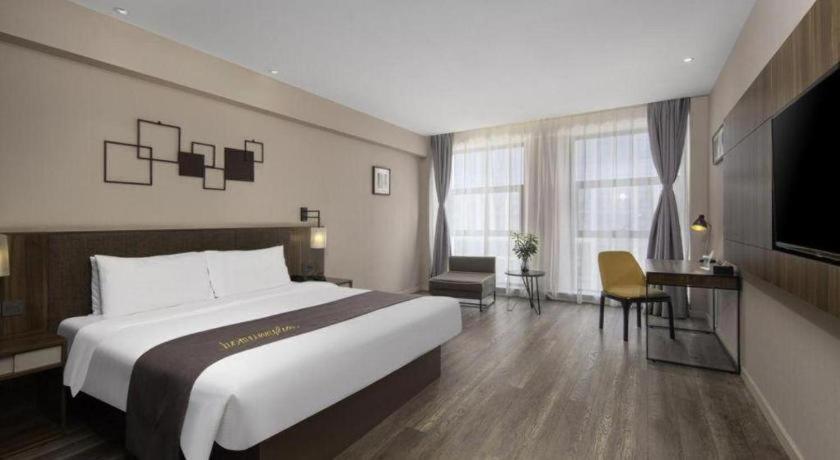 a hotel room with a large bed and a desk at Campanile Hotel Dongying Financial Port in Dongying