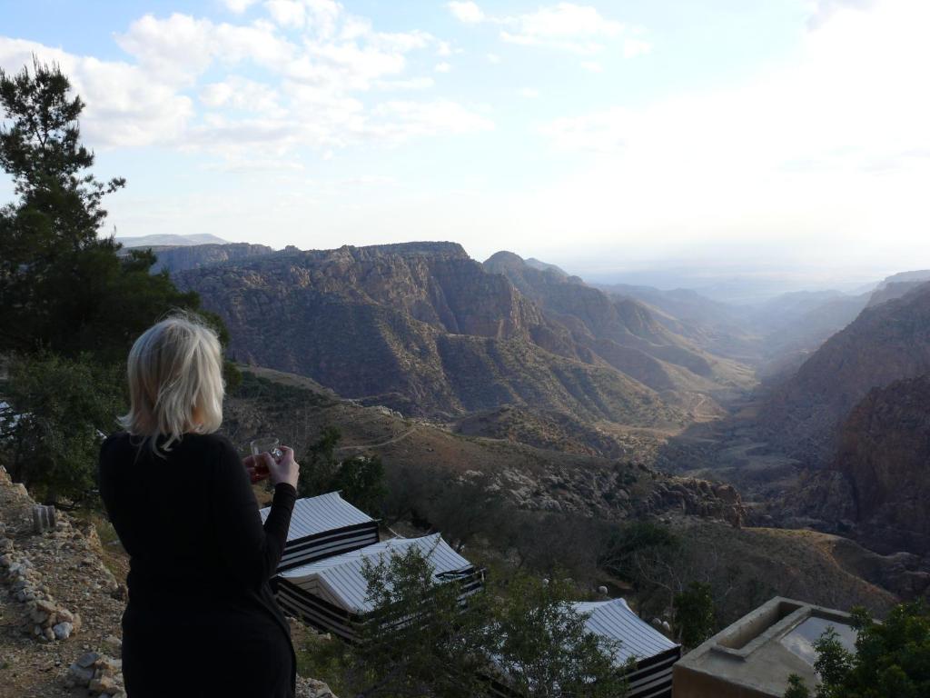 una mujer parada en la cima de una montaña mirando el cañón en Dana Village Camp-Wadi Dana Eco camp, en Dana