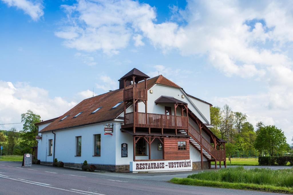 a white building with a wooden roof on a street at Penzion Country Steak Restaurant in Lanškroun