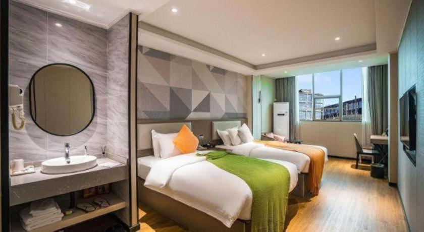 吉安市にあるBorrman Hotel Ji'an Railway Station Jinggangshan Universityのベッド2台と洗面台があるホテルの部屋