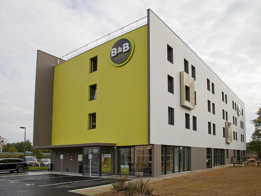 een groot geel gebouw met een bbc-bord erop bij B&B HOTEL Nantes Savenay in Savenay