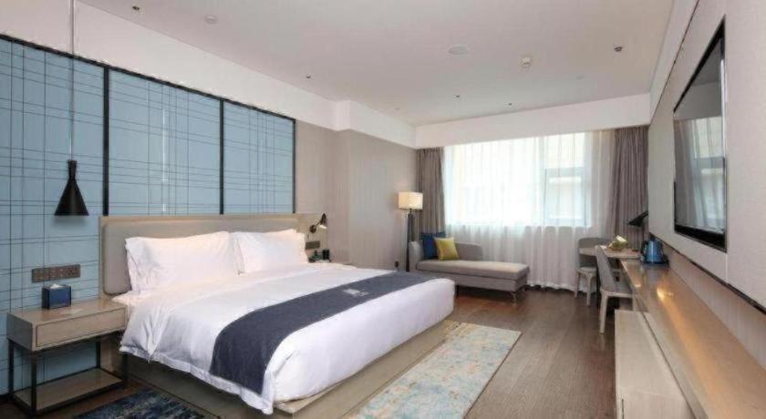 a bedroom with a large white bed and a desk at Echarm Hotel Chengdu Happy Valley Southwest Jiaotong University in Chengdu