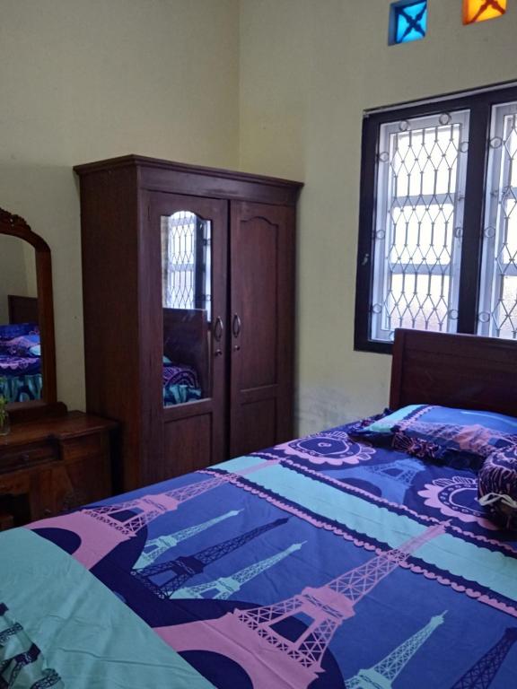 Schlafzimmer mit einem Bett, einem Schrank und einem Spiegel in der Unterkunft POTT Homestay in Godean