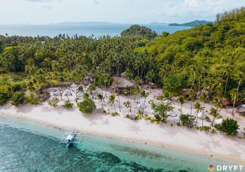 eine Luftaufnahme eines Strandes mit einem Boot im Wasser in der Unterkunft Dryft Darocotan Island in El Nido