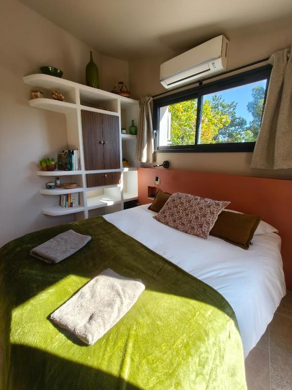 Un dormitorio con una gran cama blanca con ventana. en La Grange d'Andrea, en Saint-Étienne-de-Fontbellon