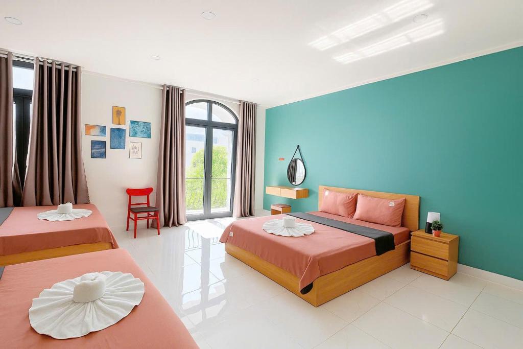 富国Ju-Jo Homestay的一间卧室，有两张床和一面蓝色的墙