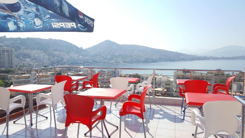 a balcony with red and white tables and chairs at Hotel Villa Zeneli in Sarand&euml;