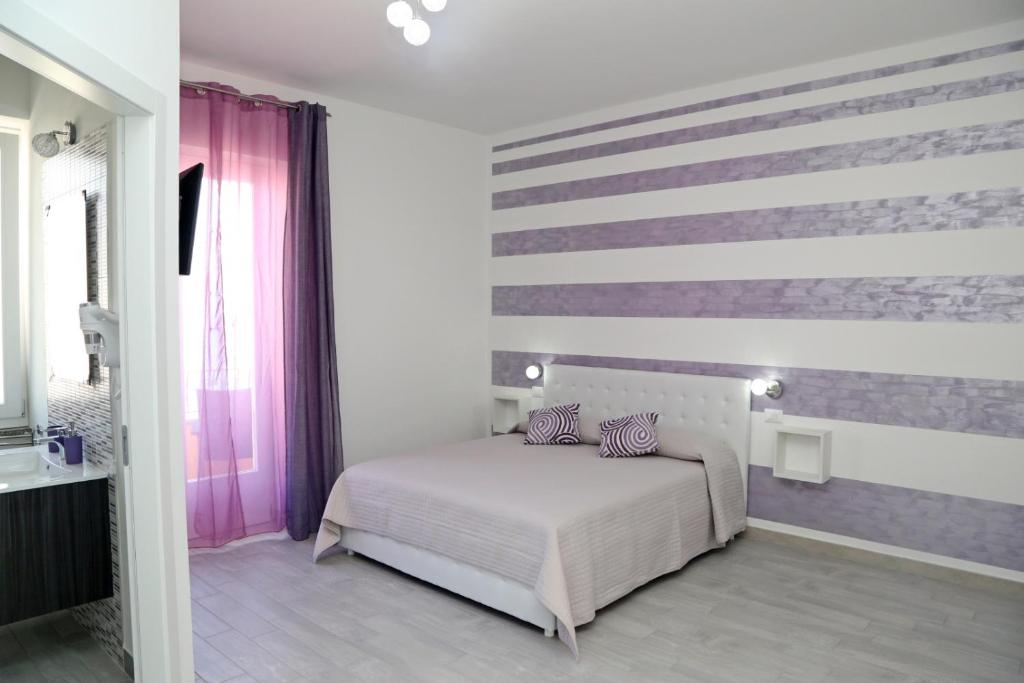 a bedroom with a bed and a striped wall at B&B Mimì in Castelsardo
