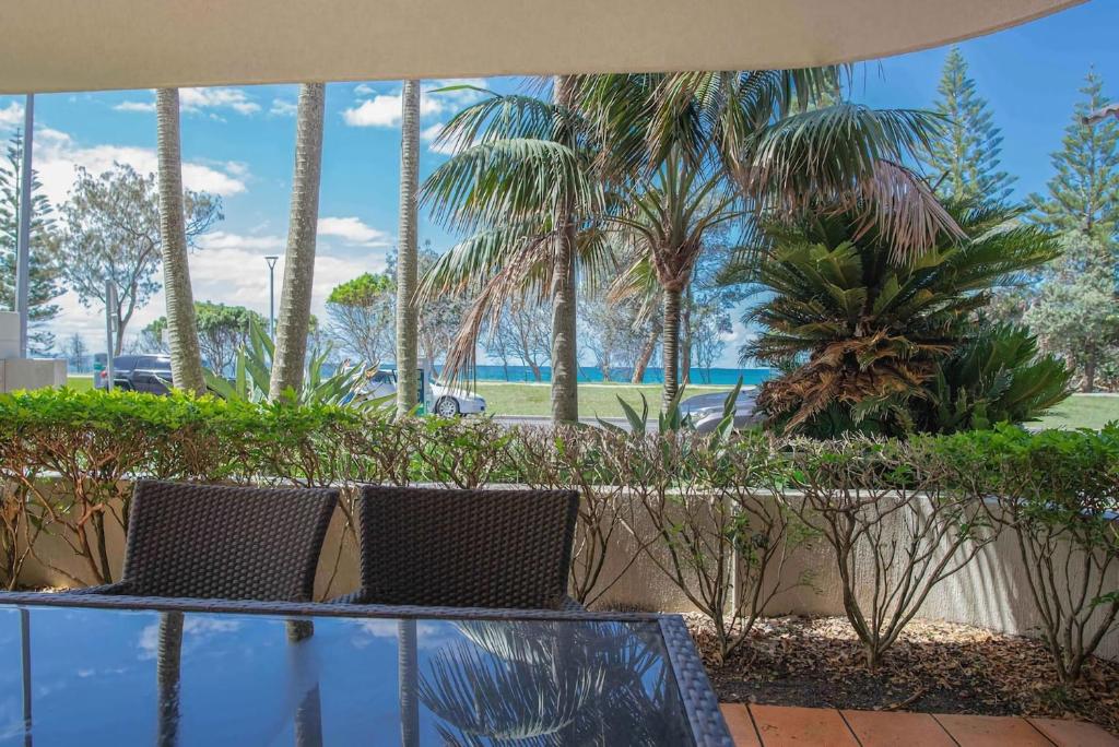 a view of palm trees from a patio with two chairs at Nautilus 1 - 1- 46 Lawson Street in Byron Bay