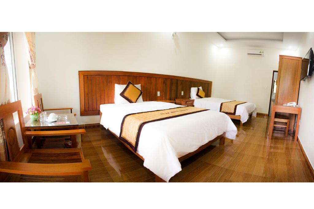 a hotel room with two beds and a table at Hoa Binh Hotel in Dong Hoi