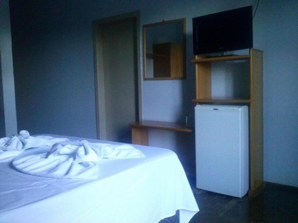 a bedroom with a white bed and a television at Ouro Preto Hotel in Restinga Sêca