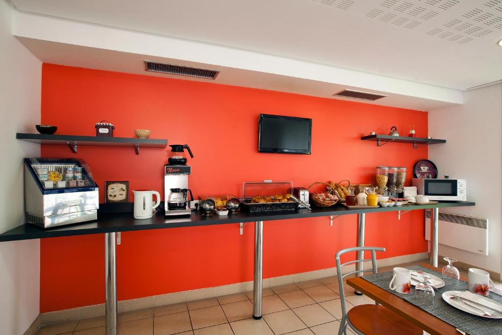 a kitchen with an orange wall with a counter at Séjours &amp; Affaires Paris Ivry in Ivry-sur-Seine