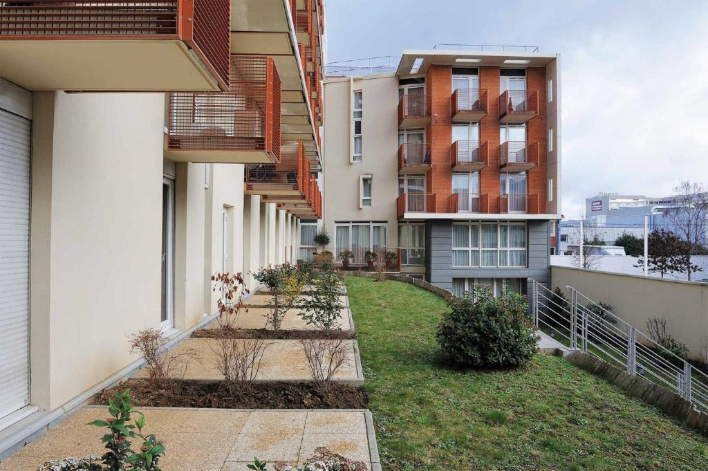 a courtyard of an apartment building with some plants at Séjours &amp; Affaires Paris Ivry in Ivry-sur-Seine