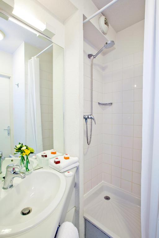 a white bathroom with a sink and a shower at Séjours &amp; Affaires Paris Ivry in Ivry-sur-Seine
