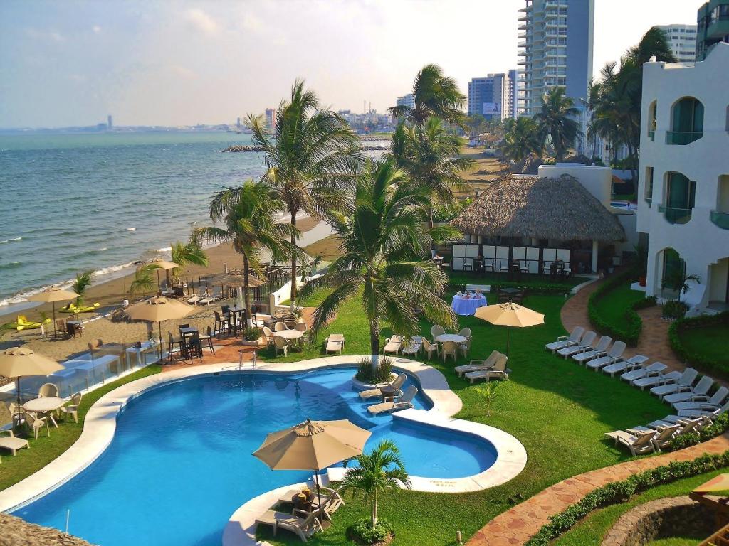 an aerial view of a resort with a swimming pool and the ocean at Playa Caracol Hotel & Spa in Veracruz