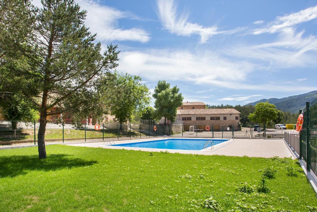 a swimming pool in a yard with a green lawn at Alberg La Sala in La Pobla de Lillet