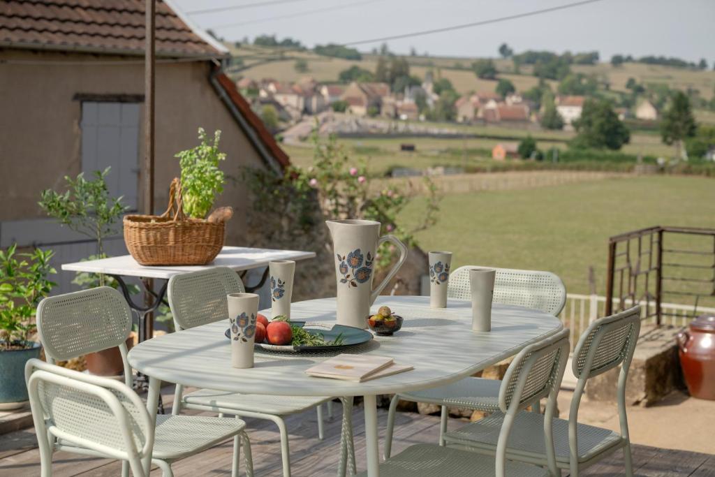 un tavolo con sedie e un piatto di frutta su un patio di Le Petit Civry a Saint-Julien-de-Civry